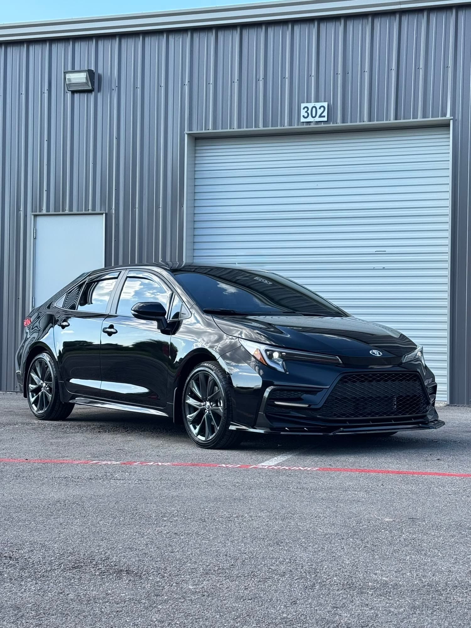 Blacked out Toyota Corolla with tinted windows parked outside the TINTEC shop bay door