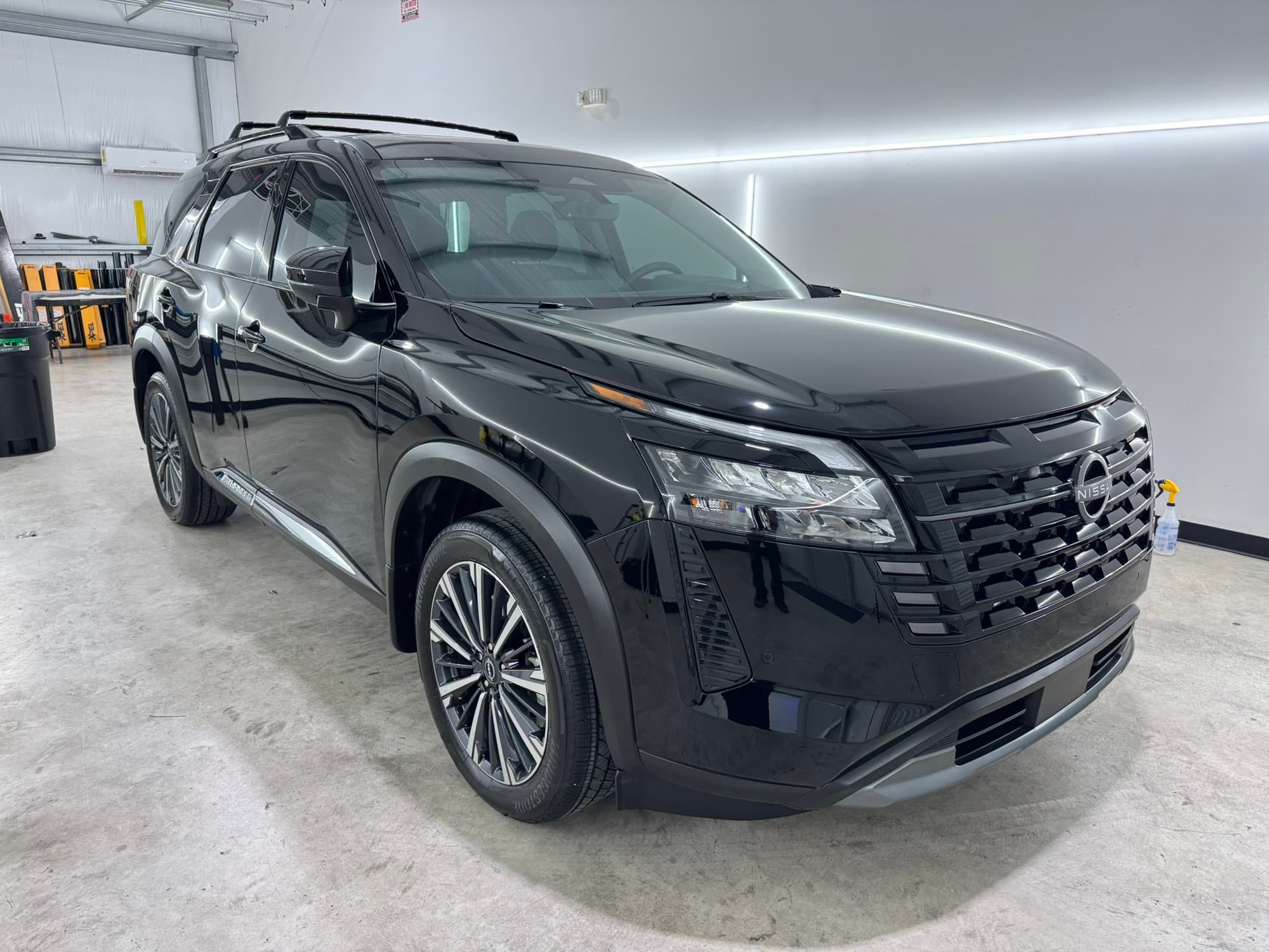 Black Nissan Pathfinder with a ceramic coated finish reflecting the overhead light bars