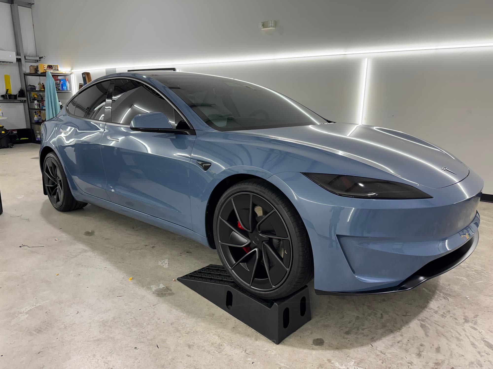 Blue Tesla Model 3 Performance on ramps in the bay, front three quarter view after paint protection work